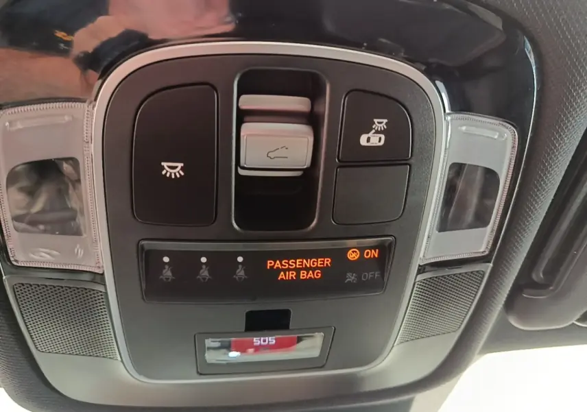 Vue rapprochée du panneau de commandes au plafond du Hyundai Tucson rouge, avec indicateur airbag passager allumé.