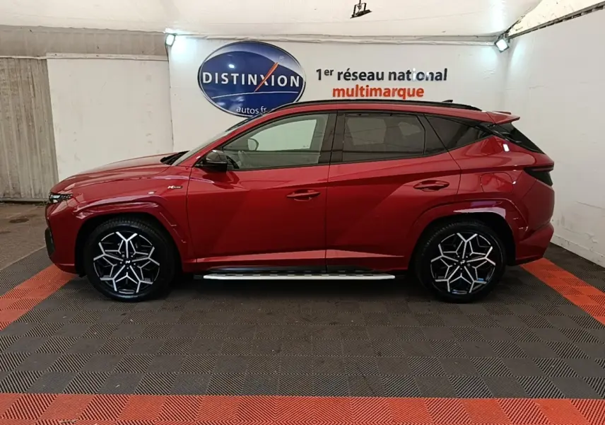 Hyundai Tucson rouge vue de profil côté gauche, avec jantes noires et détails N Line visibles.