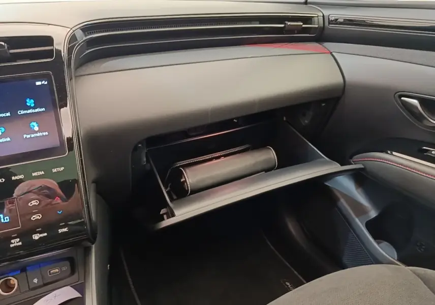 Intérieur du Hyundai Tucson 2022, vue côté passager sur la boîte à gants ouverte avec un étui noir à l'intérieur.