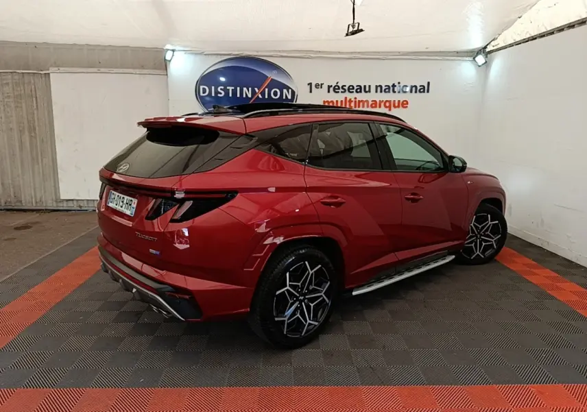 Hyundai Tucson rouge 2022 en 3/4 arrière droit, avec jantes noires et toit noir contrasté.