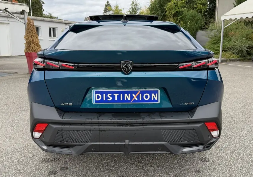 Vue arrière d'une Peugeot 408 PHEV 225 GT bleu 2023 avec feux LED et logo lion central sur parking.