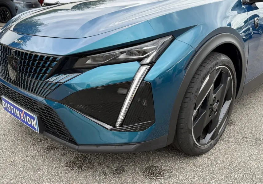 Vue 3/4 avant droit du Peugeot 408 PHEV 225 GT bleu avec phares LED et jante noire distinctive.