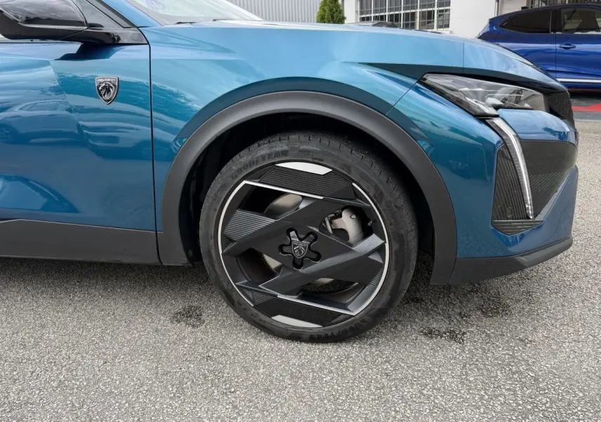 Gros plan sur la roue avant droite et l’aile avant bleu métallisé du Peugeot 408 PHEV 225 GT 2023.