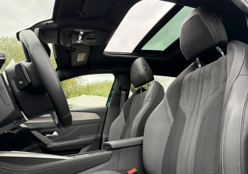 Vue intérieure côté gauche du Peugeot 408 PHEV 225 GT 2023 avec sièges gris et toit ouvrant panoramique.