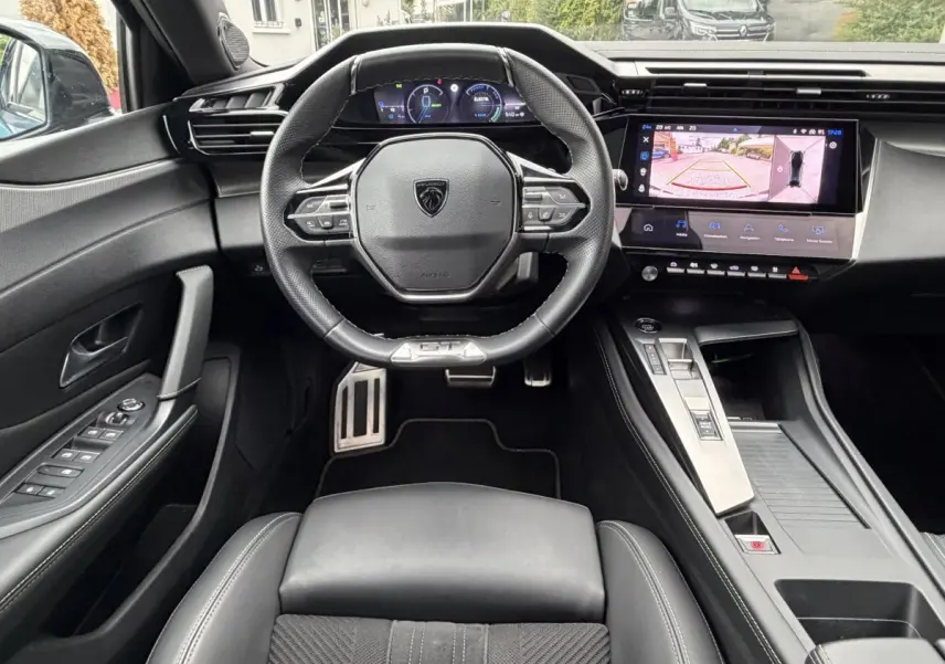 Vue intérieure frontale du poste de conduite noir du Peugeot 408 PHEV 225 GT avec écran tactile et volant multifonctions.