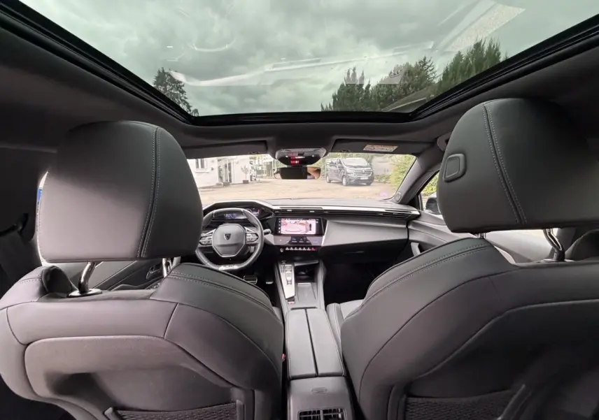 Vue intérieure arrière du Peugeot 408 PHEV 225 GT 2023, sièges noirs et toit panoramique vitré.
