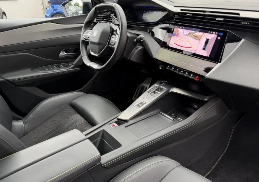 Intérieur noir de la Peugeot 408 PHEV 225 GT vu côté conducteur, avec écran tactile affichant la caméra de recul.