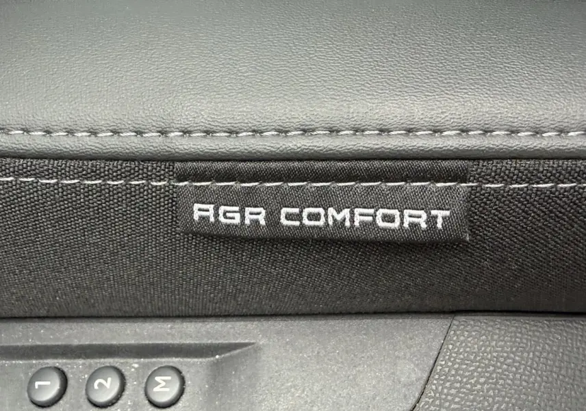 Détail intérieur montrant l'étiquette AGR Comfort sur siège tissu noir avec commandes mémoire de réglage.