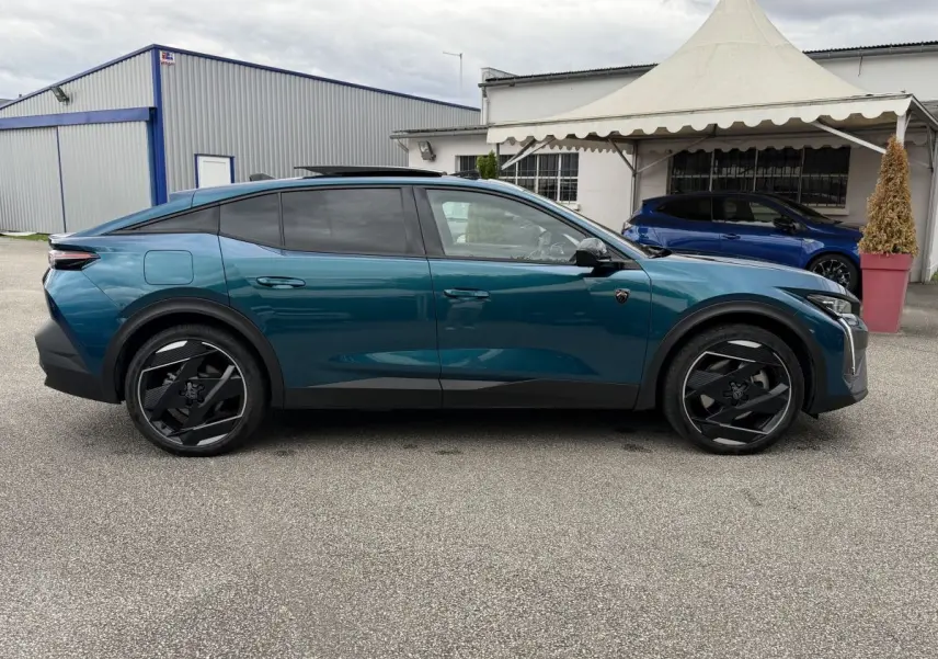 Vue de profil côté gauche d’une Peugeot 408 PHEV 225 GT bleu avec jantes noires au design futuriste.