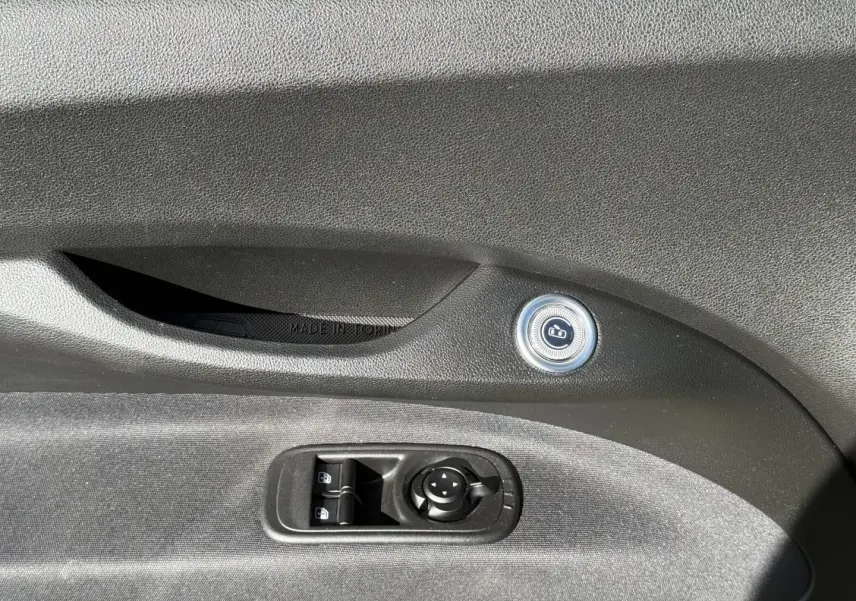Détail de la commande de verrouillage et des réglages des rétroviseurs sur la porte côté conducteur d'une FIAT 500 e jaune.