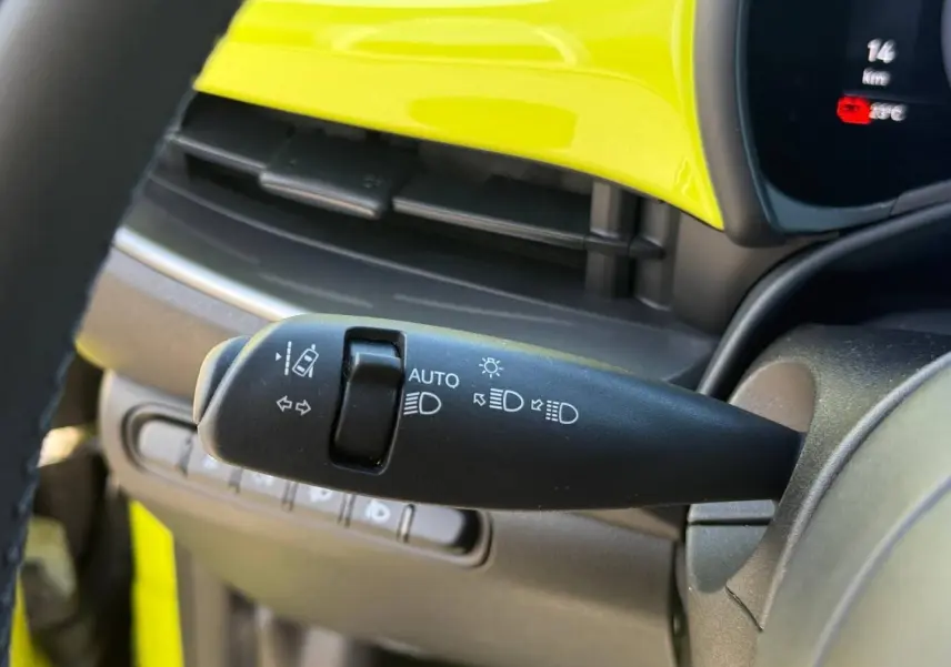 Gros plan sur la commande des feux avec tableau de bord jaune vif de la Fiat 500 électrique 2024.