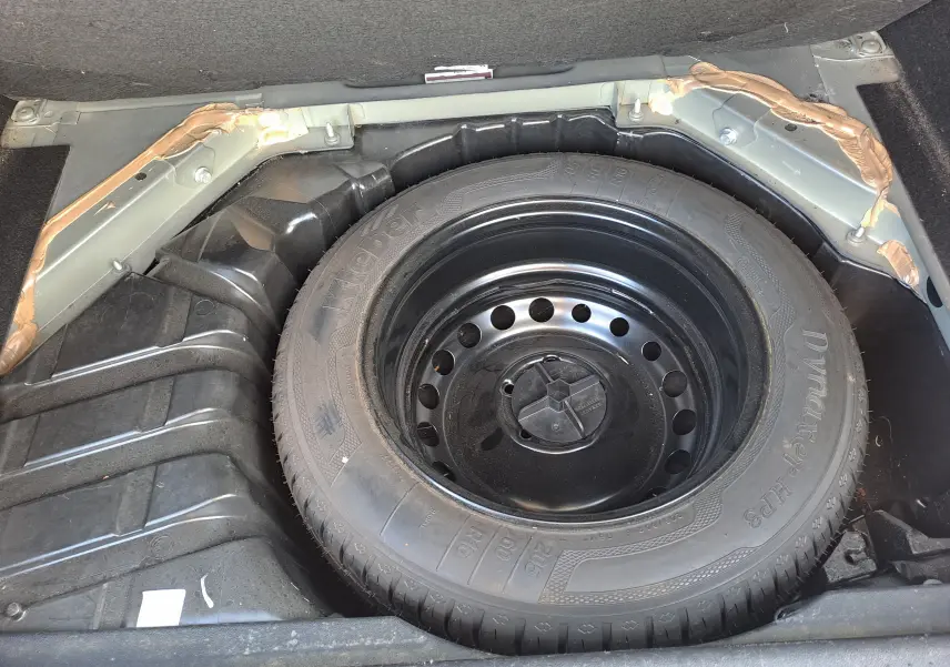 Vue rapprochée de la roue de secours noire dans le coffre d’un Renault Scenic III gris 2016.