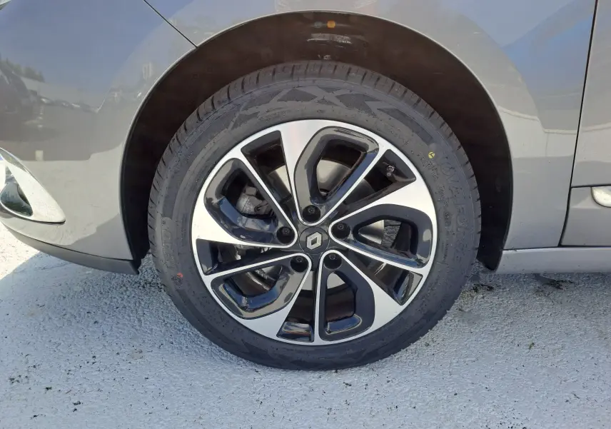 Gros plan sur la roue avant gauche grise d'un Renault Scenic III 1.2 TCE 130CH Intens avec jante alliage bicolore.
