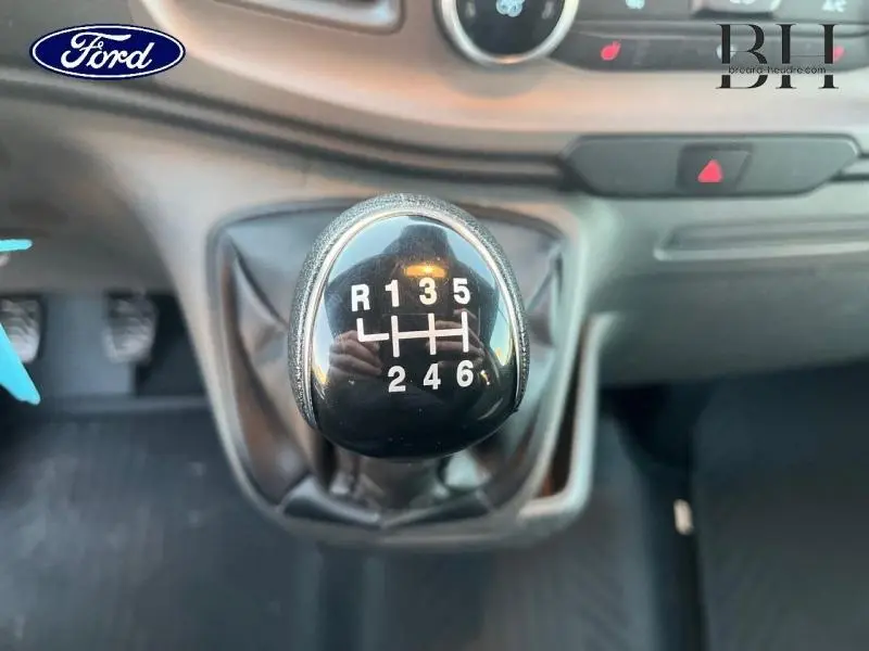 Gros plan sur le levier de vitesses manuel noir du Ford Transit Custom gris Magnétic 2023, avec console de bord en arrière-plan.