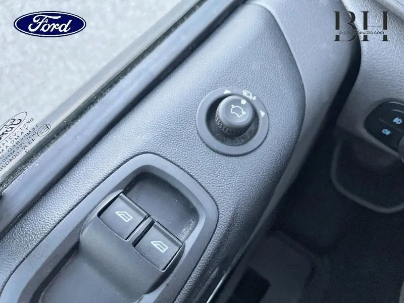 Gros plan sur les commandes de réglage des rétroviseurs et des vitres côté conducteur du Ford Transit Custom gris métallisé.