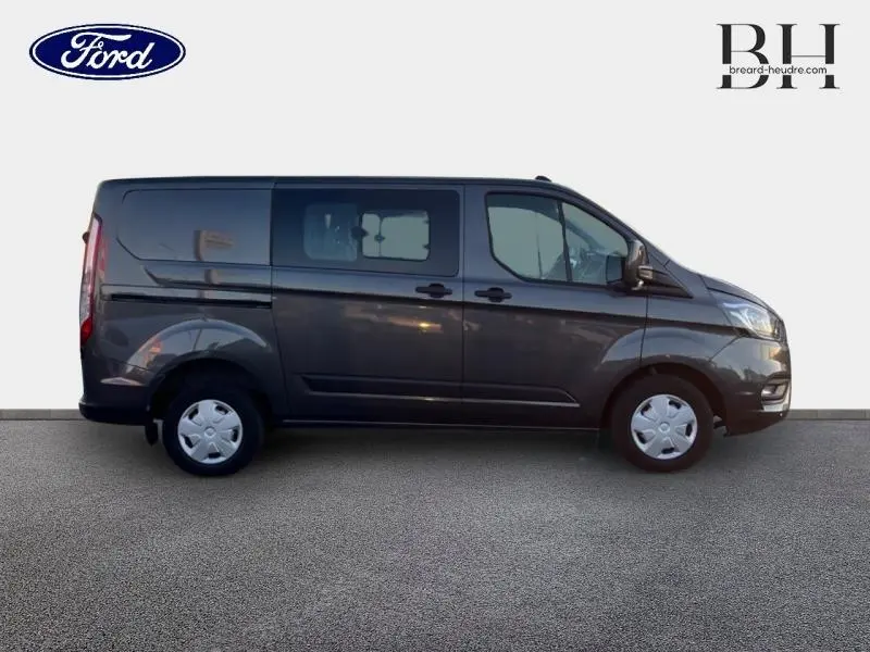 Profil côté droit du Ford Transit Custom Fourgon gris Magnétic métallisé 2023 avec portes coulissantes et vitres teintées.