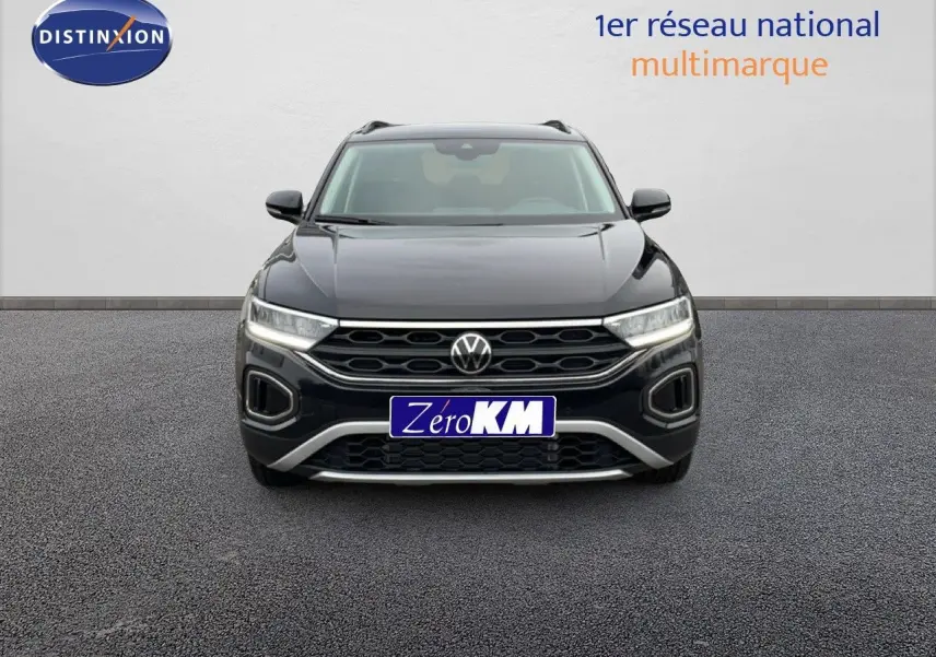 Vue frontale d'un Volkswagen T-Roc noir grenadilla métallisé avec calandre hexagonale et phares LED allumés.