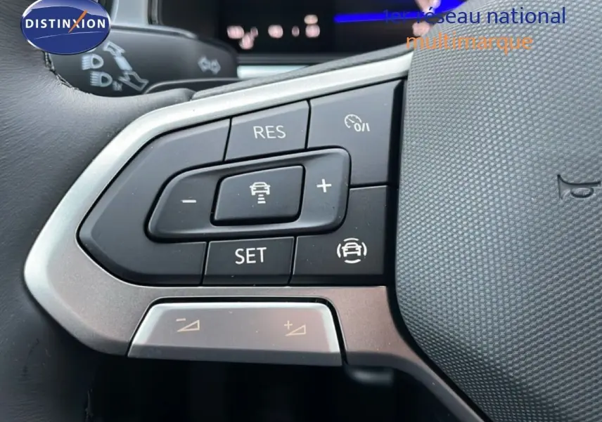 Gros plan sur les commandes au volant du Volkswagen T-Roc 1.5 TSI noir Grenadilla, mettant en valeur les boutons de régulateur de vitesse.