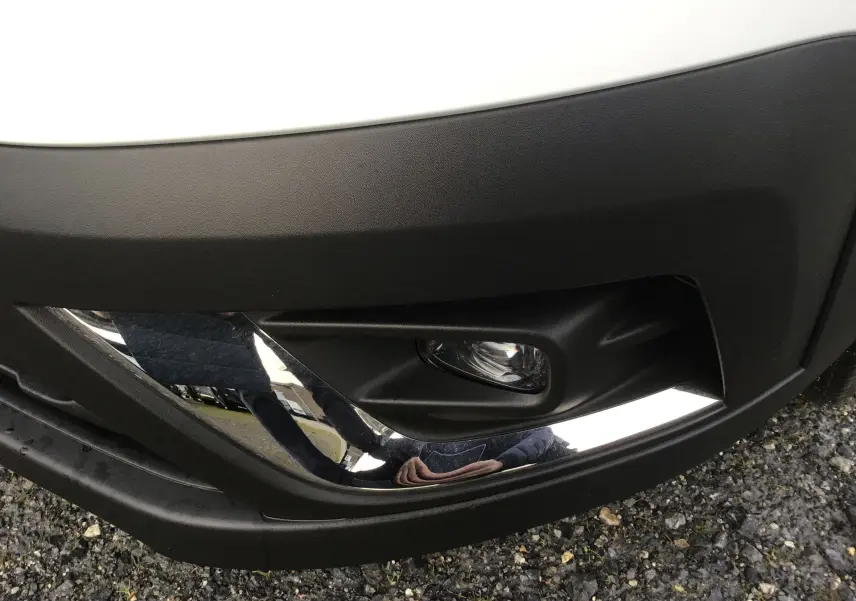 Gros plan sur le feu antibrouillard avant droit du Renault Trafic Fourgon blanc, avec insert chromé et pare-chocs noir.