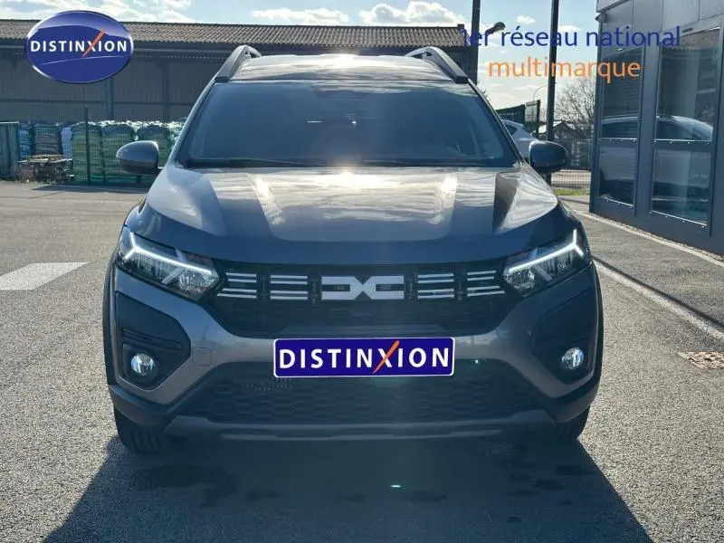 Vue avant d'un Dacia Jogger gris schiste métallisé 2025 avec calandre noire et feux LED allumés.