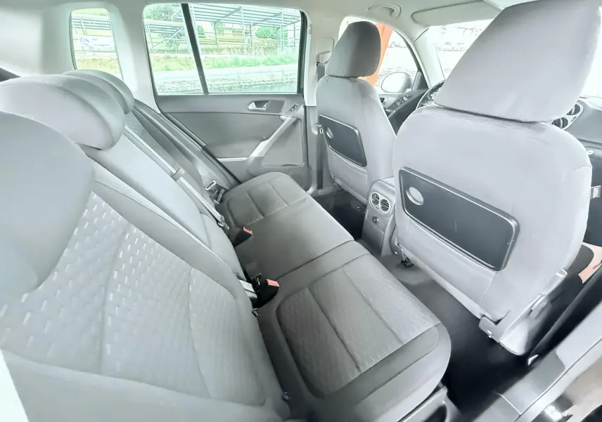 Vue intérieure arrière du Volkswagen Tiguan 2007 noir, montrant les sièges arrière en tissu gris et les dossiers avant avec rangements.