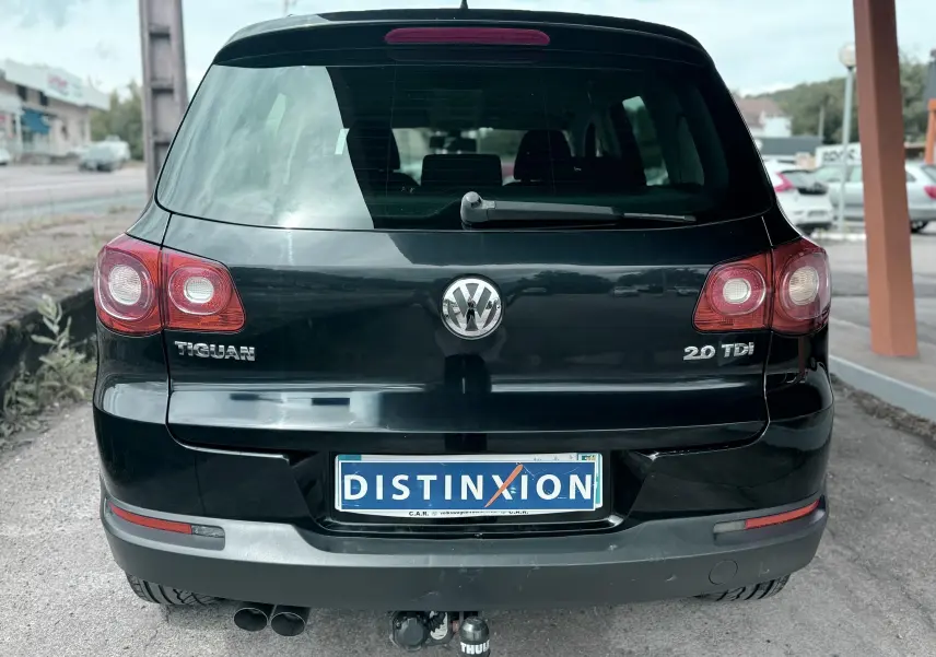 Vue arrière d’un Volkswagen Tiguan noir 2.0 TDI avec attelage et plaque Distinxion visible.