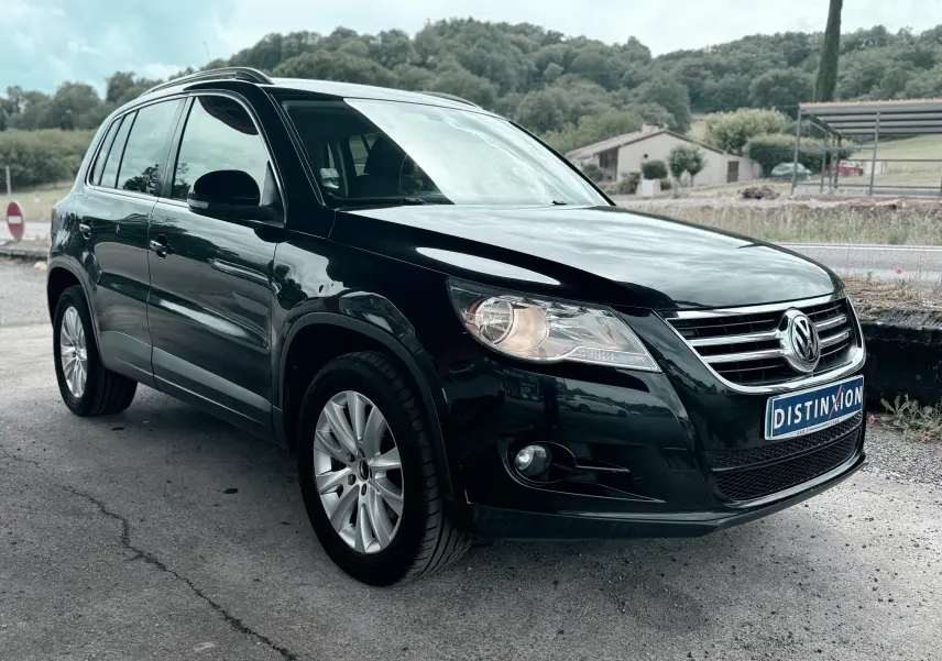 Volkswagen Tiguan noir vu en 3/4 avant droit, avec jantes alliage et calandre chromée visible.