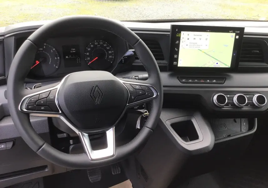 Vue intérieure centrée sur le volant et le tableau de bord du Renault Master blanc avec écran tactile et commandes au volant.