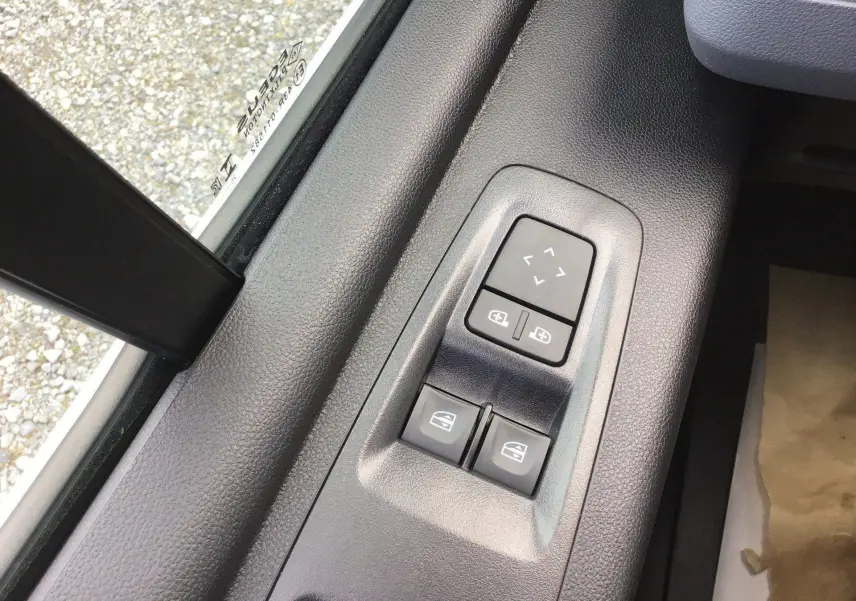 Gros plan sur les commandes de réglage des rétroviseurs et des vitres électriques côté conducteur du Renault Master blanc.