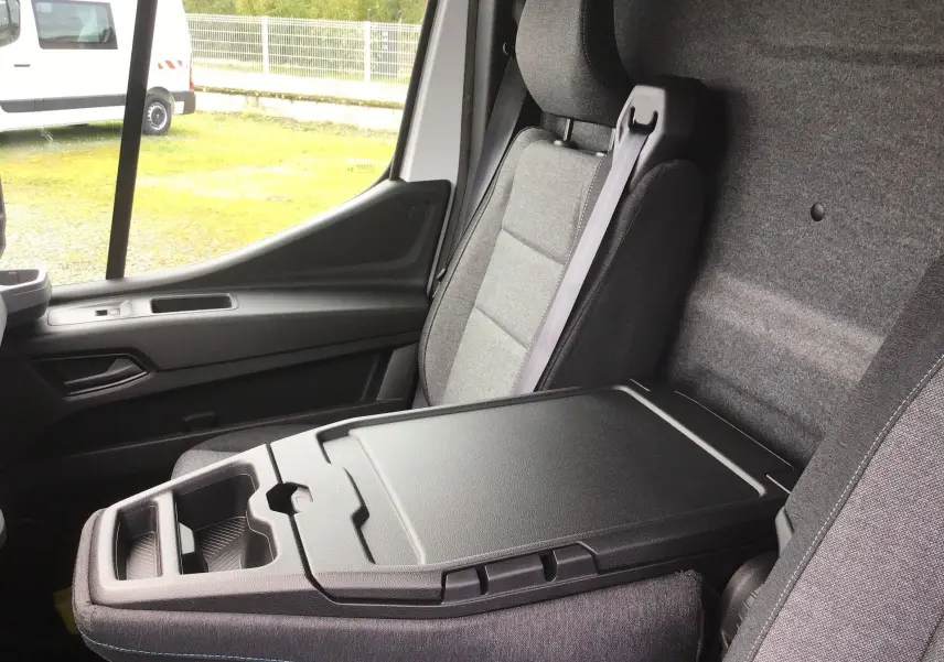 Intérieur du Renault Master blanc, vue côté passager montrant la banquette avec bureau mobile et accoudoir fermé.