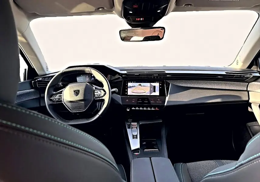 Vue intérieure avant du Peugeot 408 noir 2025, avec tableau de bord moderne et écran tactile affichant la caméra de recul.