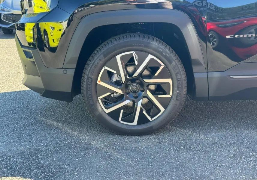 Gros plan sur la roue avant gauche du Jeep Compass Vulcano noire, avec jante alu bicolore et pneu Michelin.