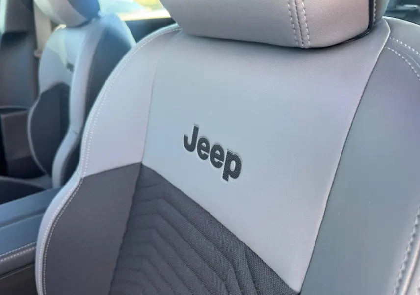 Gros plan sur le siège avant gris et anthracite avec logo Jeep brodé, mettant en valeur la finition intérieure du Compass.