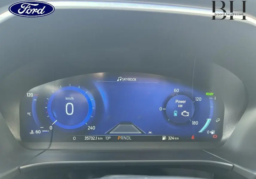 Vue rapprochée du tableau de bord numérique du Ford Kuga 2023, affichage bleu avec compteur km/h et indicateurs hybrides.