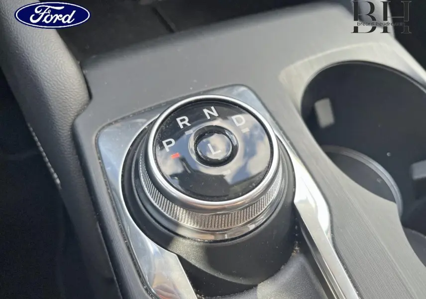 Gros plan sur la molette de sélection de la boîte automatique du Ford Kuga noir Agate, avec porte-gobelets à droite.