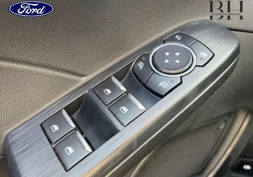 Gros plan sur les commandes de lève-vitres et réglages des rétroviseurs côté conducteur du Ford Kuga 2023 noir Agate.