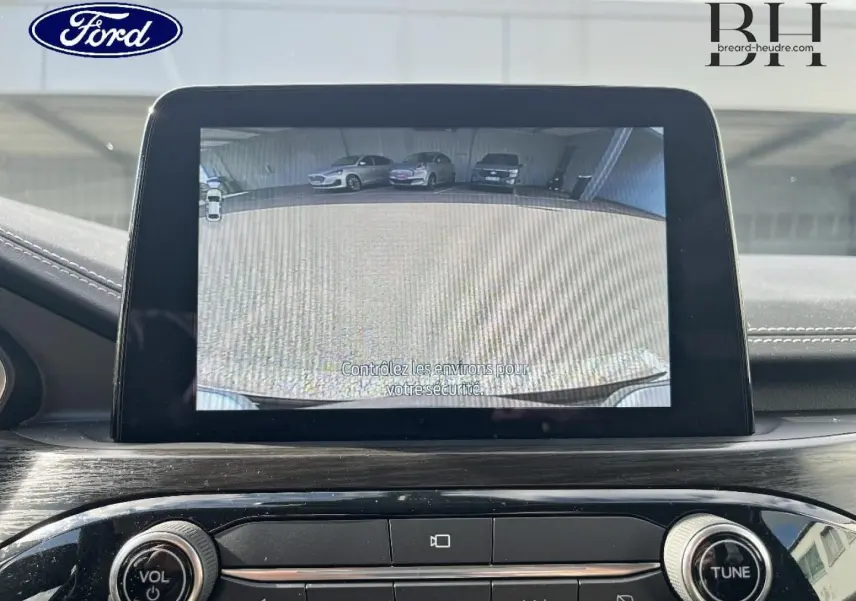 Écran tactile intérieur montrant la caméra de recul du Ford Kuga noir Agate, tableau de bord moderne avec commandes audio.