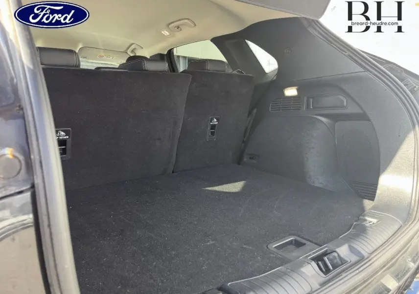 Coffre ouvert vu de l'arrière droit du Ford Kuga noir Agate Métallisée avec banquette arrière relevée.