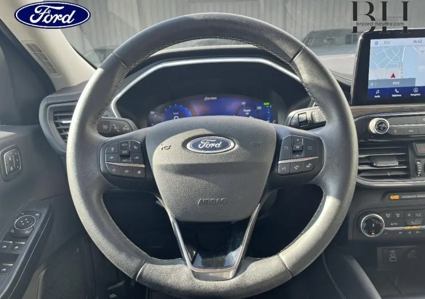 Vue intérieure centrée sur le volant cuir noir du Ford Kuga 2023 avec tableau de bord digital et écran tactile GPS.