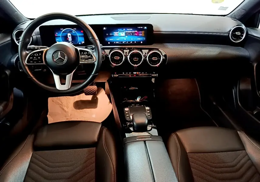 Vue intérieure avant de la Mercedes Classe A 180 d Business Line 2021, tableau de bord noir avec écran tactile et volant cuir multifonctions.