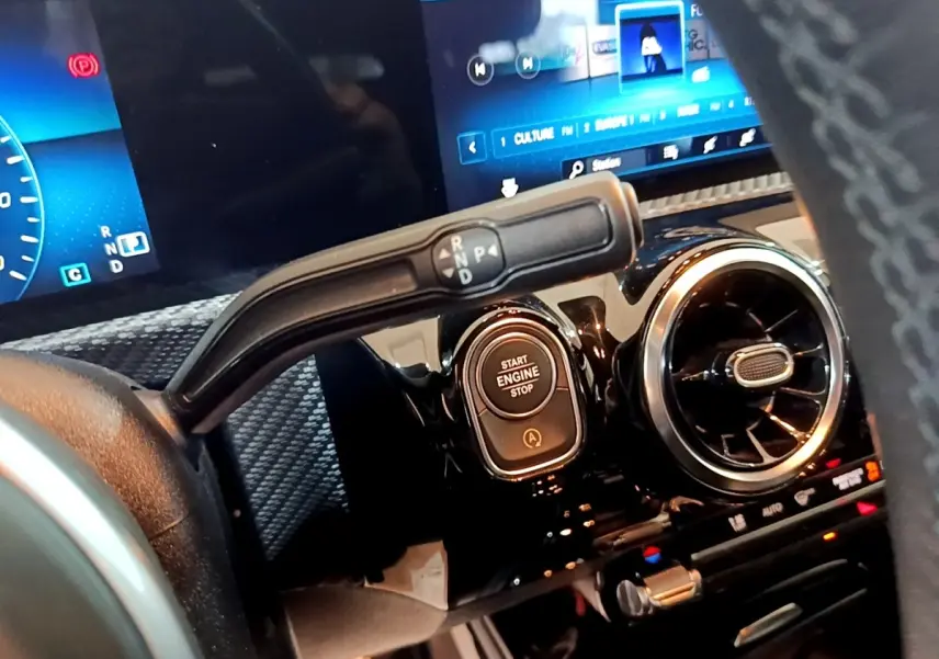 Gros plan intérieur sur la commande de boîte auto et bouton start/stop d'une Mercedes Classe A gris foncé, tableau de bord numérique.