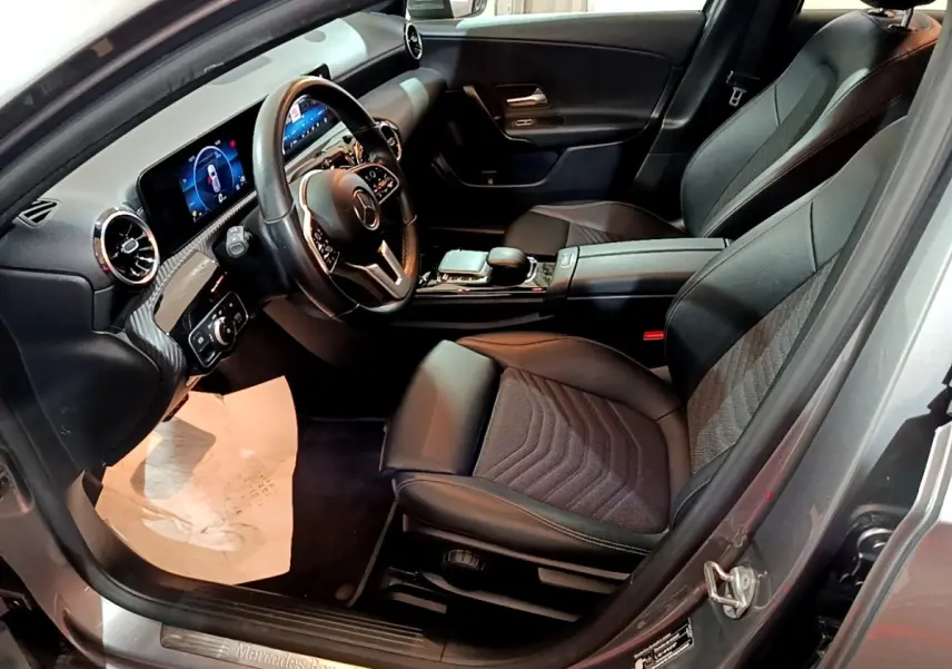 Vue intérieure côté conducteur d'une Mercedes Classe A 180 d Business Line 2021 gris foncé avec volant cuir multifonctions et écran tactile.