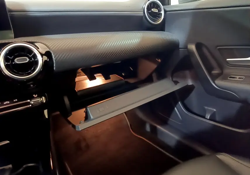 Vue intérieure côté passager de la boîte à gants ouverte, tableau de bord gris foncé texturé de la Mercedes Classe A 180 d 2021.