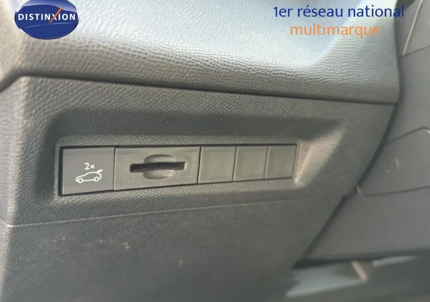 Détail du bouton d'ouverture du coffre sur le tableau de bord noir d'une Peugeot 408 gris selenium metal.