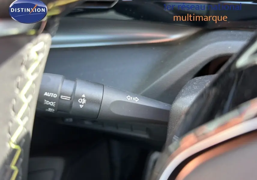 Gros plan sur la commande des clignotants à gauche du volant dans l’habitacle sombre d’une Peugeot 408 gris selenium.