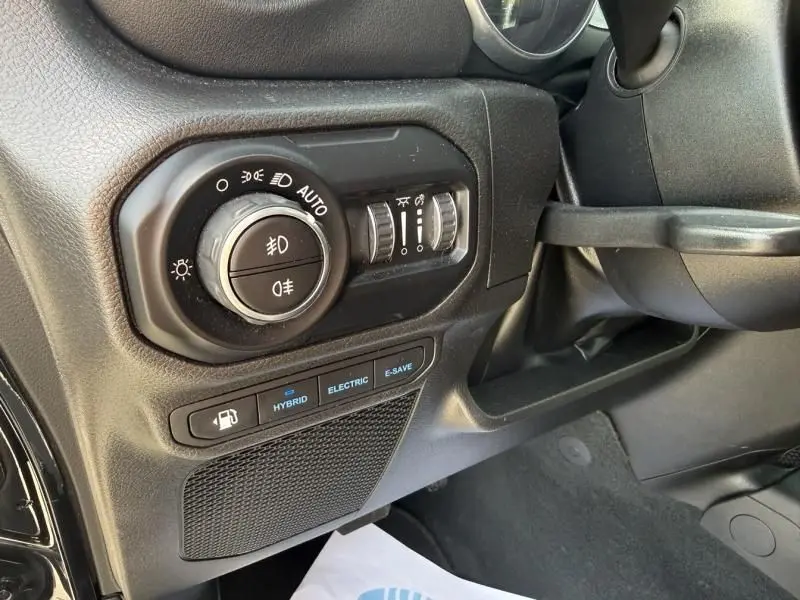 Détail du tableau de bord du Jeep Wrangler Unlimited 2022 noir, montrant les commandes d’éclairage et modes hybride.