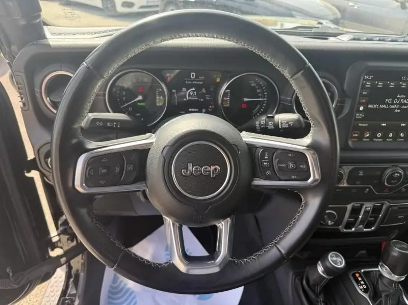 Vue intérieure centrée sur le volant noir du Jeep Wrangler 2022 avec tableau de bord et écran tactile visibles.