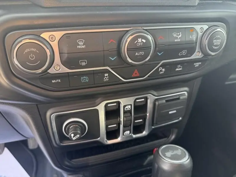 Vue rapprochée du tableau de bord noir du Jeep Wrangler Unlimited 2022, mettant en valeur les commandes de climatisation et la console centrale.