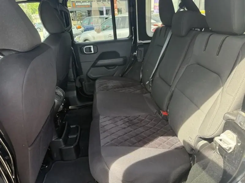 Vue intérieure côté arrière droit du Jeep Wrangler Unlimited 2022 noir, montrant la banquette arrière en tissu avec motifs matelassés.