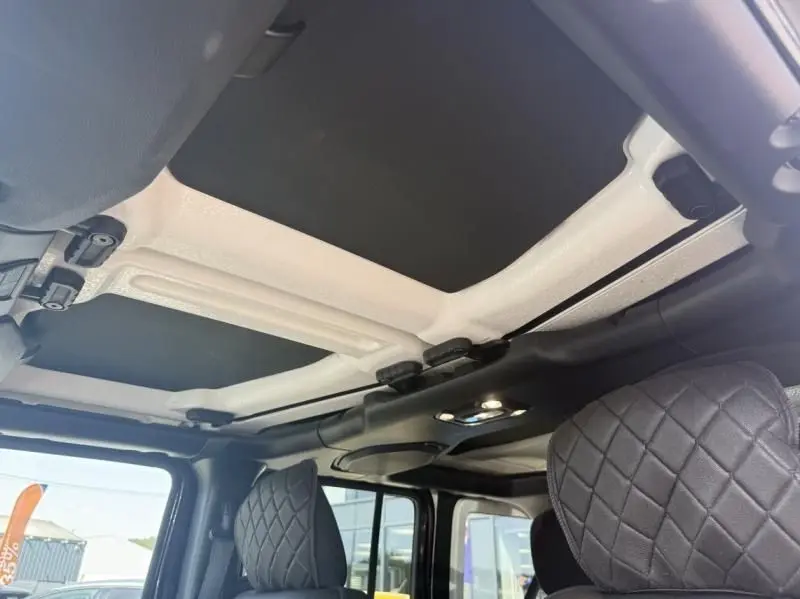Vue intérieure du toit amovible noir et blanc du Jeep Wrangler Unlimited 2022 avec sièges avant en cuir noir matelassé.